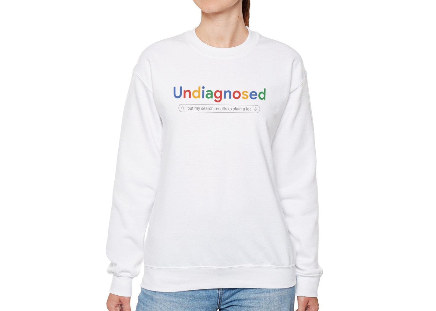 Model wearing a white sweatshirt with "Undiagnosed" in a Google-style font and a search bar graphic, standing with hands at sides. Part of the Vivid Divergence Sensory Friendly Unisex Sweater Jumper Range.