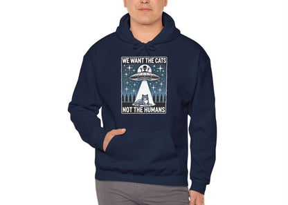 Model wearing a navy blue hoodie featuring the text "We Want the Cats, Not the Humans" with an illustration of a UFO beaming up cats. Part of the Vivid Divergence Sensory Friendly Unisex Hoodie Range.