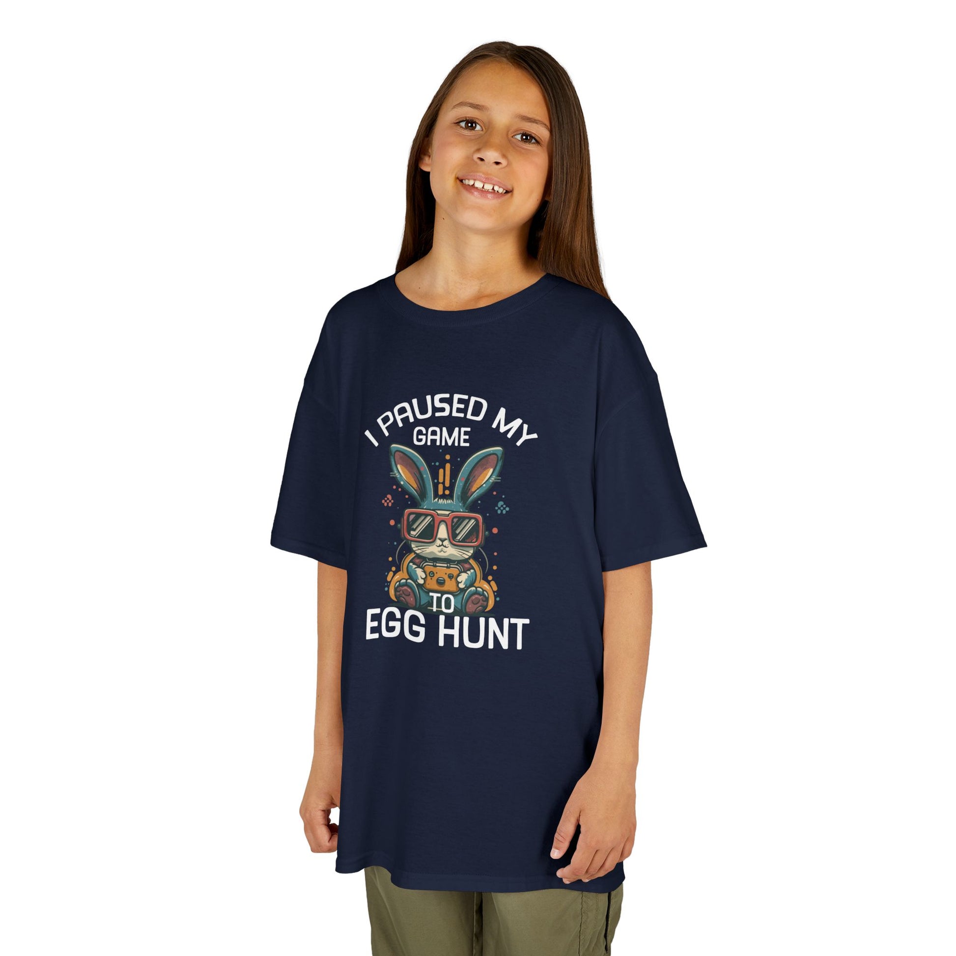 Child wearing a navy blue Easter T-shirt with "I Paused My Game to Egg Hunt" and a gaming-style bunny, a trendy holiday outfit. Hop into the season in style and shop Easter shirts online today!