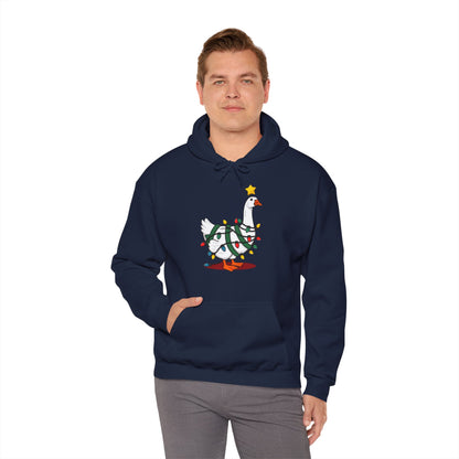 Model wearing a navy blue hoodie featuring a festive illustration of a goose wearing a Santa hat and stringing Christmas lights, with the text "Goose on the Loose." Part of the Vivid Divergence Sensory Friendly Unisex Hoodie Range.