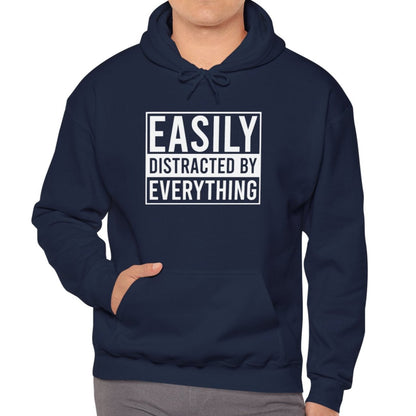 Model wearing a navy blue hoodie with the text "Easily Distracted by Everything" in bold white lettering. Part of the Vivid Divergence Sensory Friendly Unisex Hoodie Range.