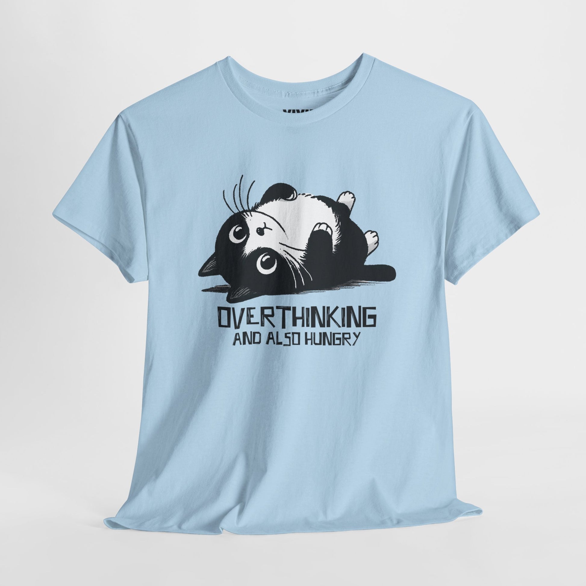 Hanging view of light blue T-shirt featuring black line art of a wide-eyed cat surrounded by scribbles, with the phrase "Overthinking and also hungry." A whole vibe. Part of the Vivid Divergence Memewear Collection!