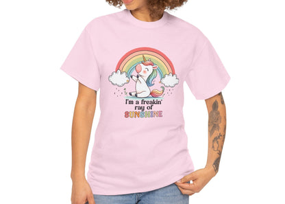 A person wearing a light pink T-shirt with a rainbow and unicorn graphic and the text "I'm A Freakin Ray Of Sunshine." Part of the Vivid Divergence Sensory Friendly Unisex Tees Range.
