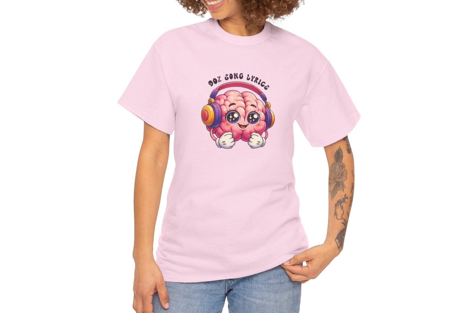 A person wearing a pink T-shirt with a colorful brain graphic, headphones, and the text "My Brain is 90% Song Lyrics." Part of the Vivid Divergence Sensory Friendly Unisex Tees Range.