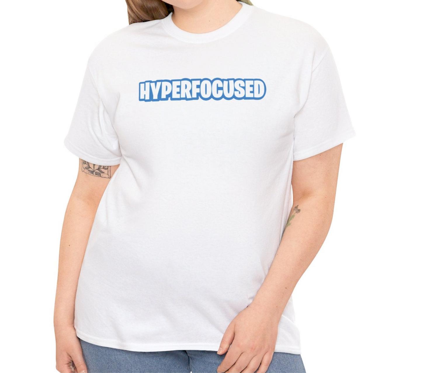 A person wearing a white T-shirt with the text "Hyperfocused" in a Fortnite-style design. Part of the Vivid Divergence Sensory Friendly Unisex Tees Range.