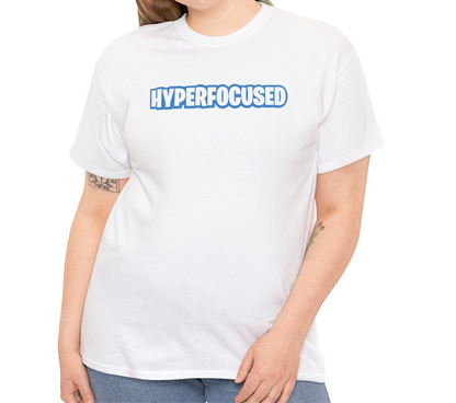 A person wearing a white T-shirt with the text "Hyperfocused" in a Fortnite-style design. Part of the Vivid Divergence Sensory Friendly Unisex Tees Range.