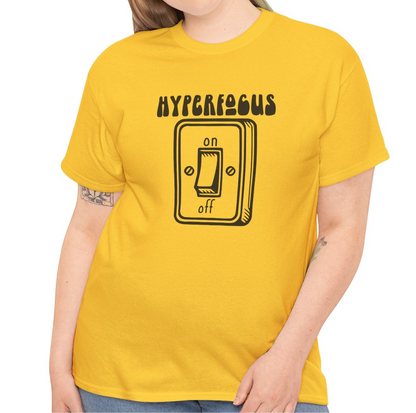 A person wearing a yellow T-shirt with the text "Hyperfocus" and an on/off switch graphic design. Part of the Vivid Divergence Sensory Friendly Unisex Tees Range.