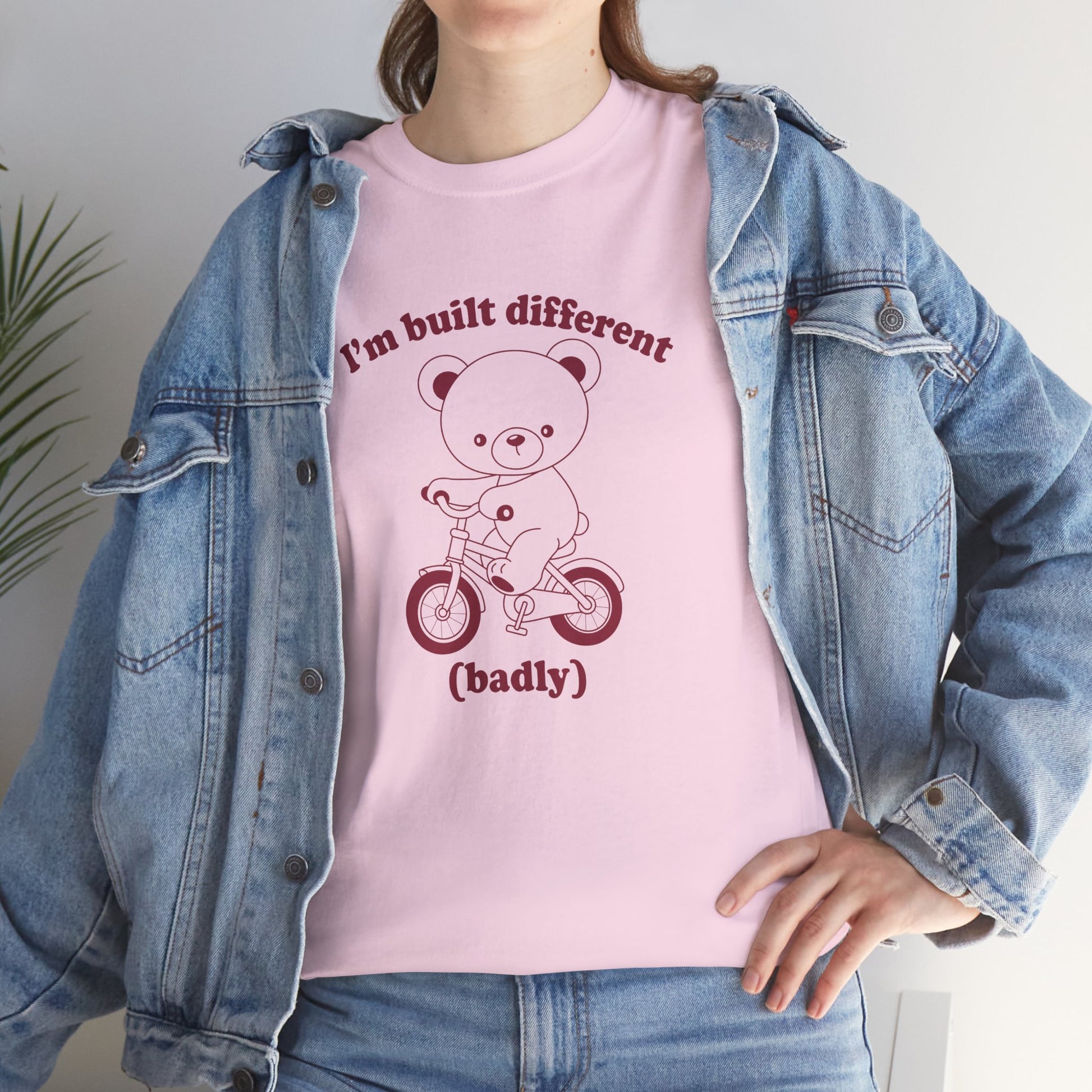 Model wearing a pink T-shirt with the "Built Different (Badly)" bear design. Part of the Vivid Divergence Sensory Friendly Unisex Tees Range.
