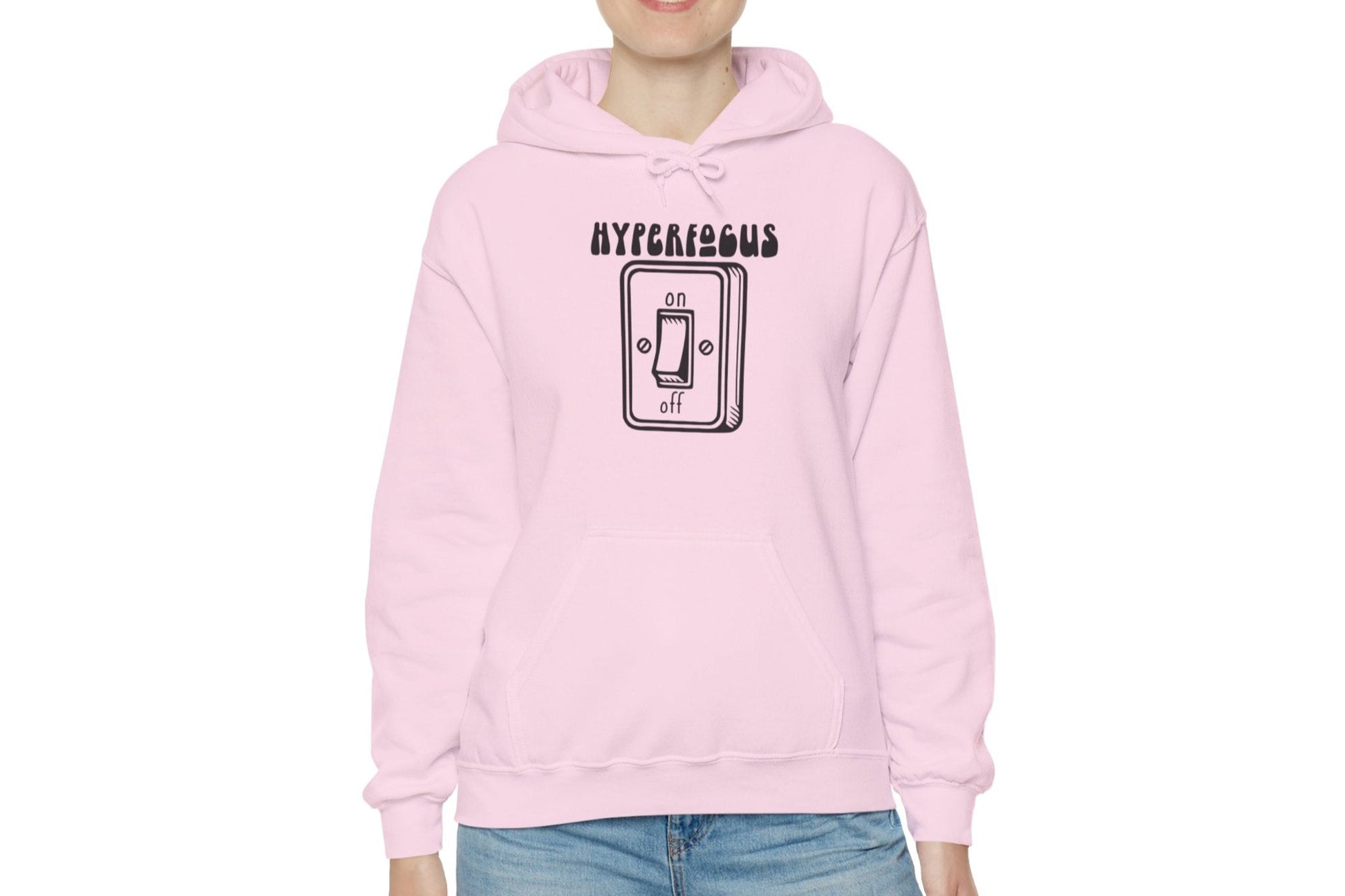 Model wearing a pink hoodie featuring the text "Hyperfocus" and an illustration of a toggle switch turned on. Part of the Vivid Divergence Sensory Friendly Unisex Hoodie Range.