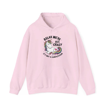 Front view of a pink hoodie featuring the text "Relax, We're All Crazy" and a cartoon illustration of a raccoon in a teacup. Part of the Vivid Divergence Sensory Friendly Unisex Hoodie Range.