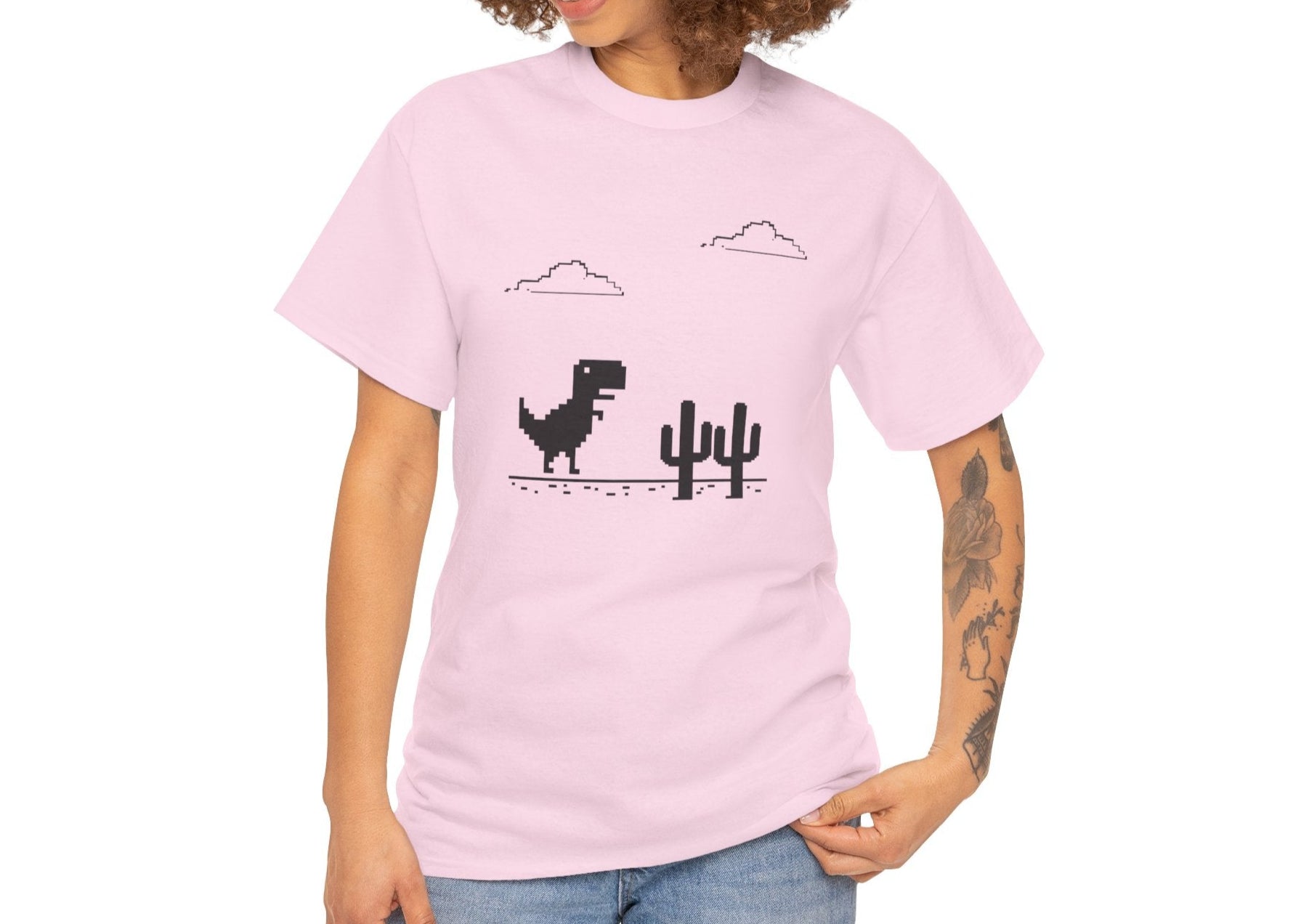 Model wearing a pink T-shirt featuring a minimalist pixel-style T-Rex Runner Dinosaur Game design with a T-Rex, cacti, and clouds. Part of the Vivid Divergence Sensory Friendly Unisex Tees Range.