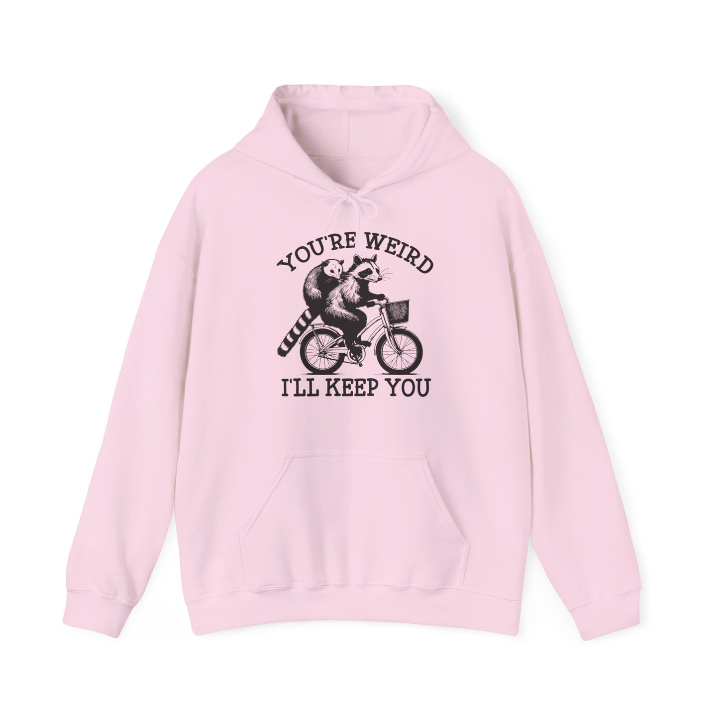 Front view of a pink hoodie featuring the text "You're Weird, I'll Keep You" with a cartoon illustration of two raccoons riding a bicycle. Part of the Vivid Divergence Sensory Friendly Unisex Hoodie Range.