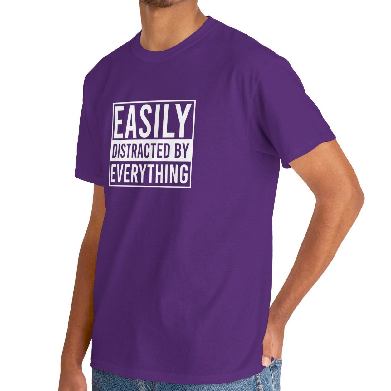 A person wearing a purple T-shirt with "Easily Distracted by Everything" text, shown from the front in a relaxed pose. Part of the Vivid Divergence Sensory Friendly Unisex Tees Range.