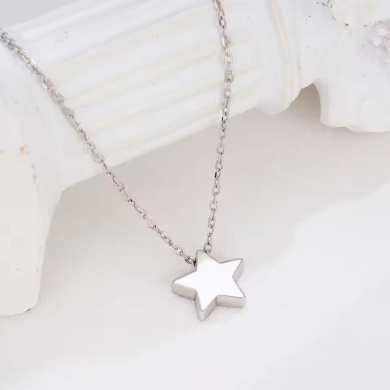 Radiant Star Necklace displayed on a white surface, highlighting its minimalist silver star pendant design.