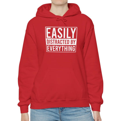 Model wearing a red hoodie with the text "Easily Distracted by Everything" in bold white lettering. Part of the Vivid Divergence Sensory Friendly Unisex Hoodie Range.