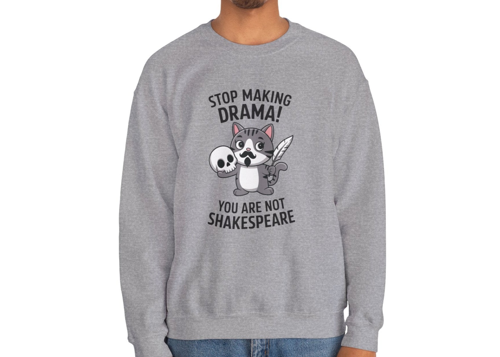 Model seated, wearing a gray sweatshirt with a cartoon cat holding a skull and the text "Stop Making Drama! You Are Not Shakespeare." Part of the Vivid Divergence Sensory Friendly Unisex Sweater Jumper Range.