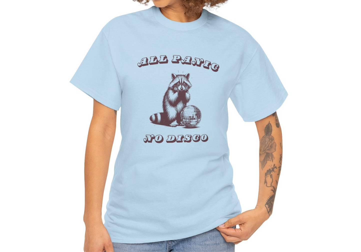 Side view of a light blue T-shirt featuring the text "All Panic No Disco" and a raccoon illustration, worn by a model. Part of the Vivid Divergence Sensory Friendly Unisex Tees Range.