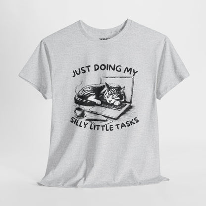 Ash gray “Just Doing My Silly Little Tasks” T-shirt hanging against neutral background. The cat is working hard (but actually sleeping). Part of the Vivid Divergence Memewear Collection!
