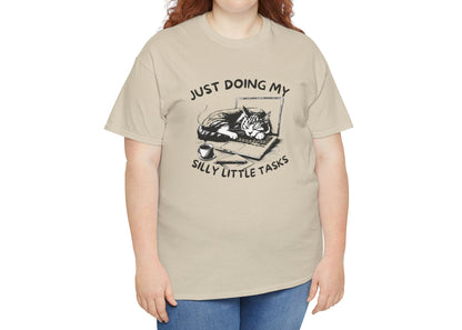 Plus-size model in beige “Just Doing My Silly Little Tasks” cat T-shirt. Comfort is the only task that matters. Part of the Vivid Divergence Memewear Collection!
