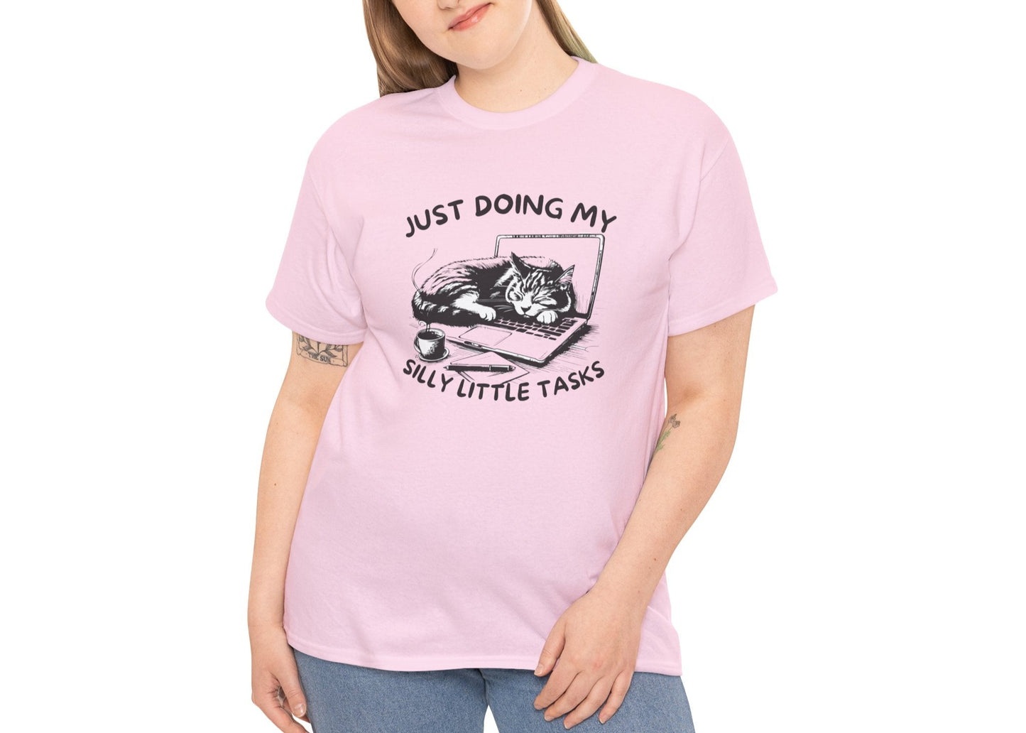 Woman in light pink cat-on-laptop T-shirt smiling with arms at sides. Currently avoiding every real responsibility. Part of the Vivid Divergence Memewear Collection!

