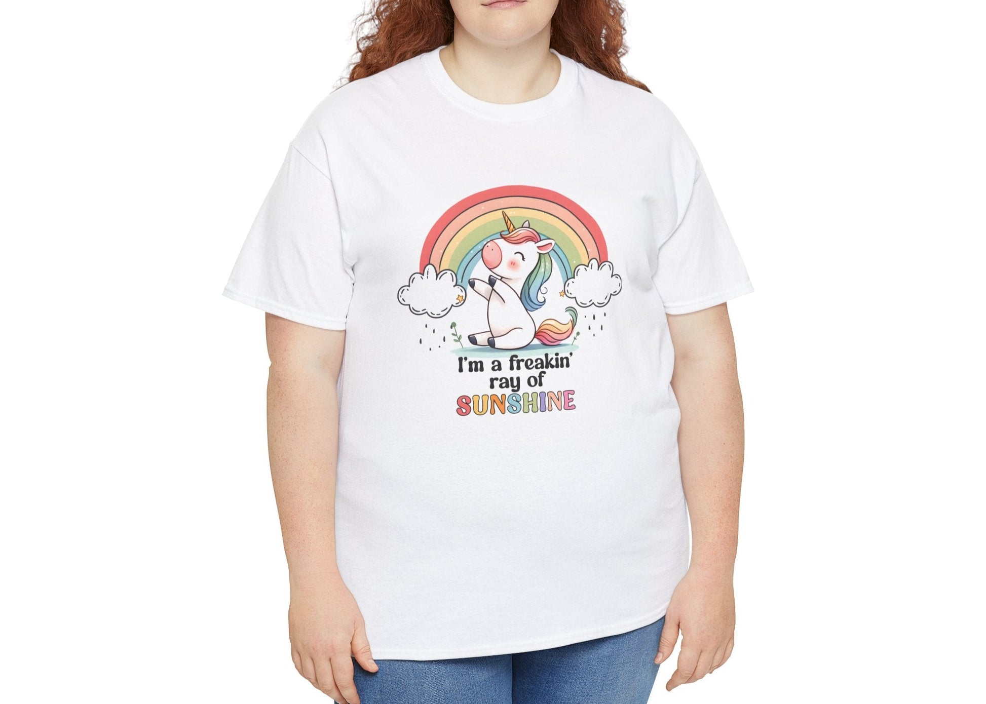 A person wearing a white T-shirt with a rainbow and unicorn graphic and the text "I'm A Freakin Ray Of Sunshine." Part of the Vivid Divergence Sensory Friendly Unisex Tees Range.
Image Name: 