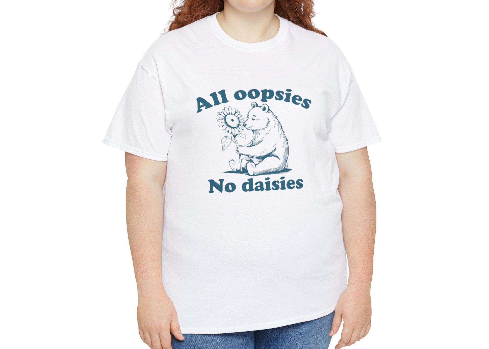Model holding up a white T-shirt with "All oopsies, no daisies" and a playful bear graphic in blue text. Part of the Vivid Divergence Sensory Friendly Unisex Tees Range. 