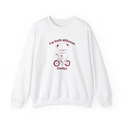 Front view of a white sweatshirt featuring a graphic of a bear riding a bike with the text "I'm Built Different (Badly)." Part of the Vivid Divergence Sensory Friendly Unisex Sweater Jumper Range.