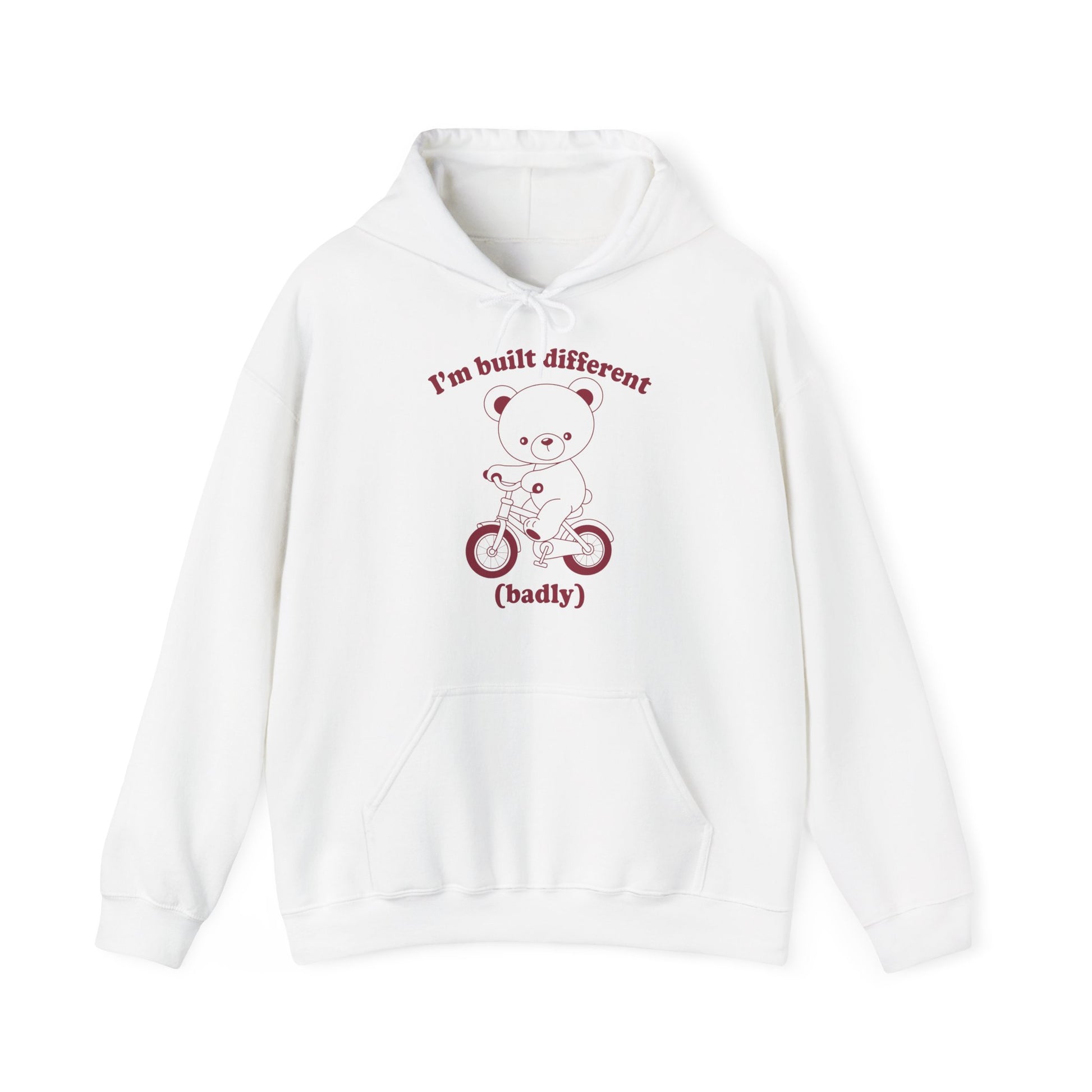 Front view of a white hoodie featuring a cartoon bear riding a small bicycle with the text "I'm Built Different (Badly)." Part of the Vivid Divergence Sensory Friendly Unisex Hoodie Range.