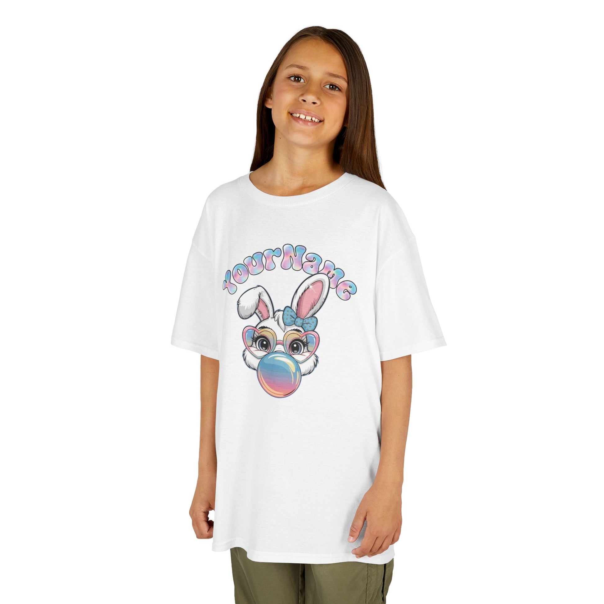 Child wearing a white Easter T-shirt with a bunny blowing bubblegum, customizable with your child's name. Looking for the perfect Easter shirts for kids? Whether you’re shopping for Easter shirts for boys, Easter shirts for girls, or Easter shirts for toddlers, we’ve got festive and fun options for everyone! Hop into the season in style and shop Easter shirts online today!
