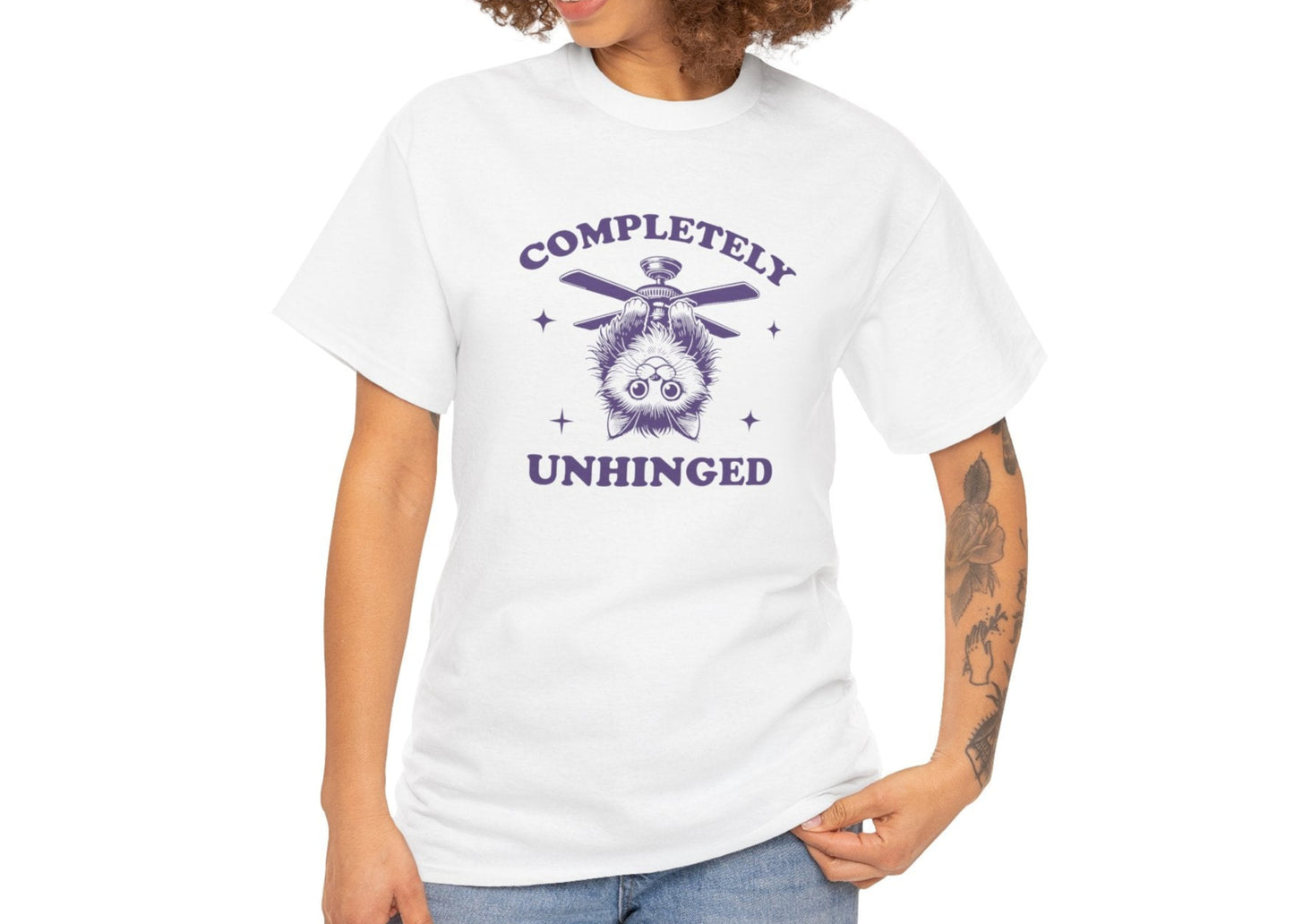 Front view of a white T-shirt featuring "Completely Unhinged" text with a cat hanging upside down from a ceiling fan in navy blue-tone design. Part of the Vivid Divergence Sensory Friendly Unisex Tees Range.