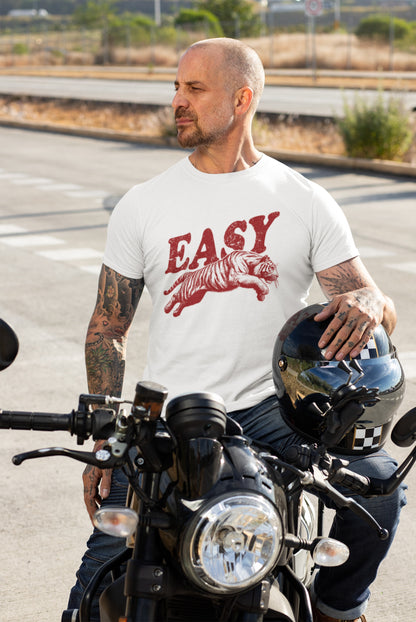 Man wearing a white T-shirt with "EASY" text and tiger illustration in black, standing beside a motorcycle. Part of the Vivid Divergence Sensory Friendly Unisex Tees Range.