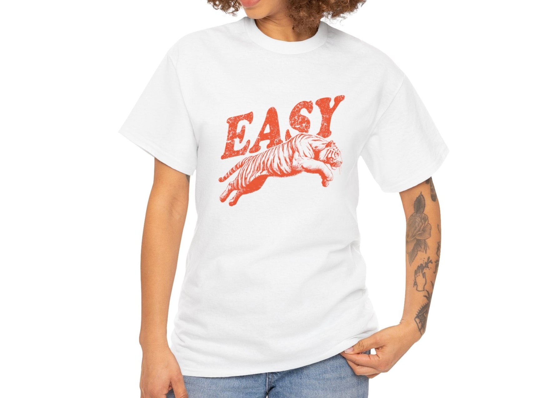 Person wearing a white T-shirt with "EASY" text and tiger illustration in red, paired with jeans. Part of the Vivid Divergence Sensory Friendly Unisex Tees Range.