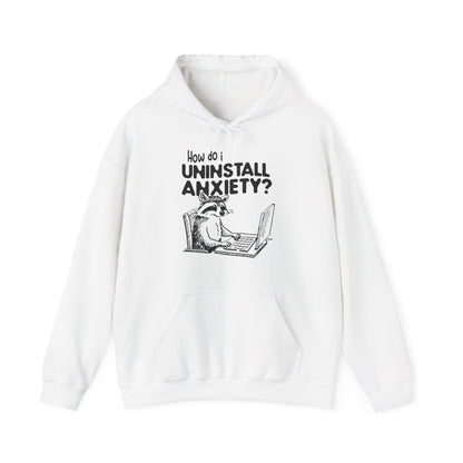 Front view of a white hoodie featuring the text "How Do I Uninstall Anxiety?" and a cartoon illustration of a raccoon using a laptop. Part of the Vivid Divergence Sensory Friendly Unisex Hoodie Range.