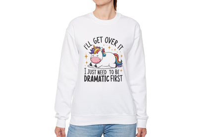 del wearing a white sweater jumper with the text "I’ll Get Over It, I Just Need To Be Dramatic First" and a cartoon unicorn lying on its side. Part of the Vivid Divergence Sensory Friendly Unisex Sweater Jumper Range.