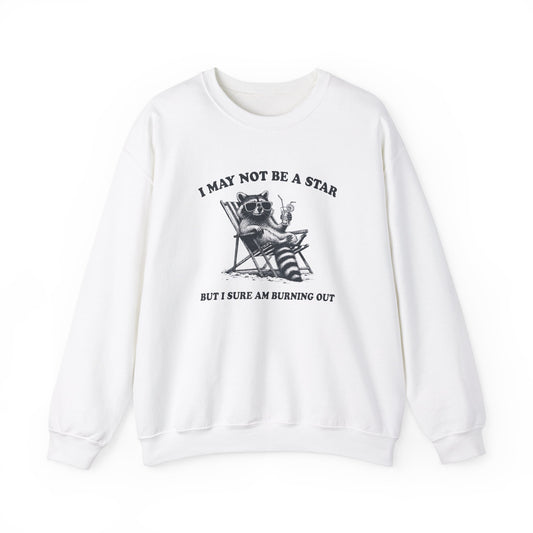 Front view of a white sweatshirt featuring a raccoon sitting in a trash can with the text "I May Not Be A Star, But I Sure Am Burning Out." Part of the Vivid Divergence Sensory Friendly Unisex Sweater Jumper Range.