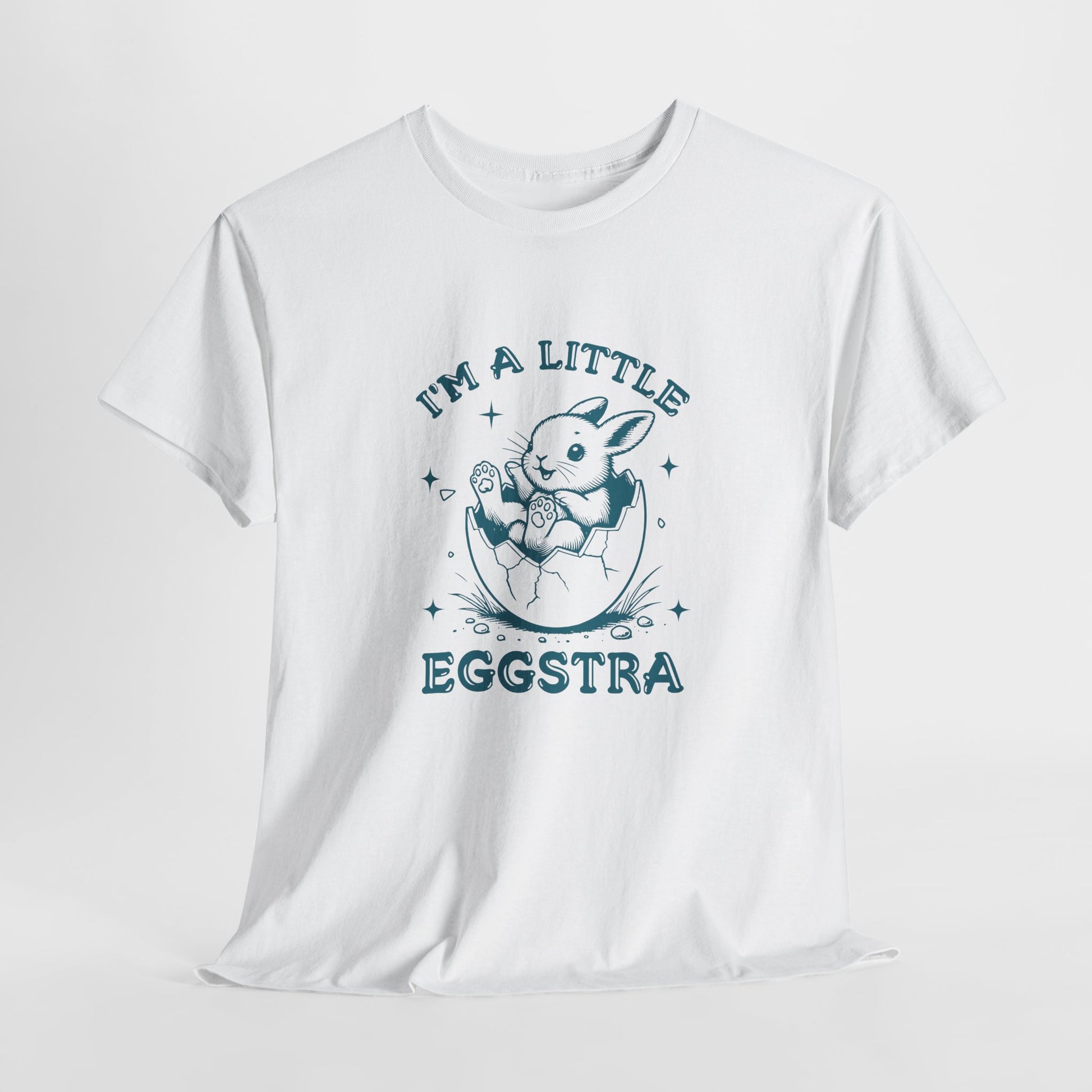 White Easter T-shirt hanging, featuring a cute bunny and "I'm A Little Eggstra" text in a blue design, perfect for a fun holiday look. Hop into the season in style and shop Easter shirts online today!