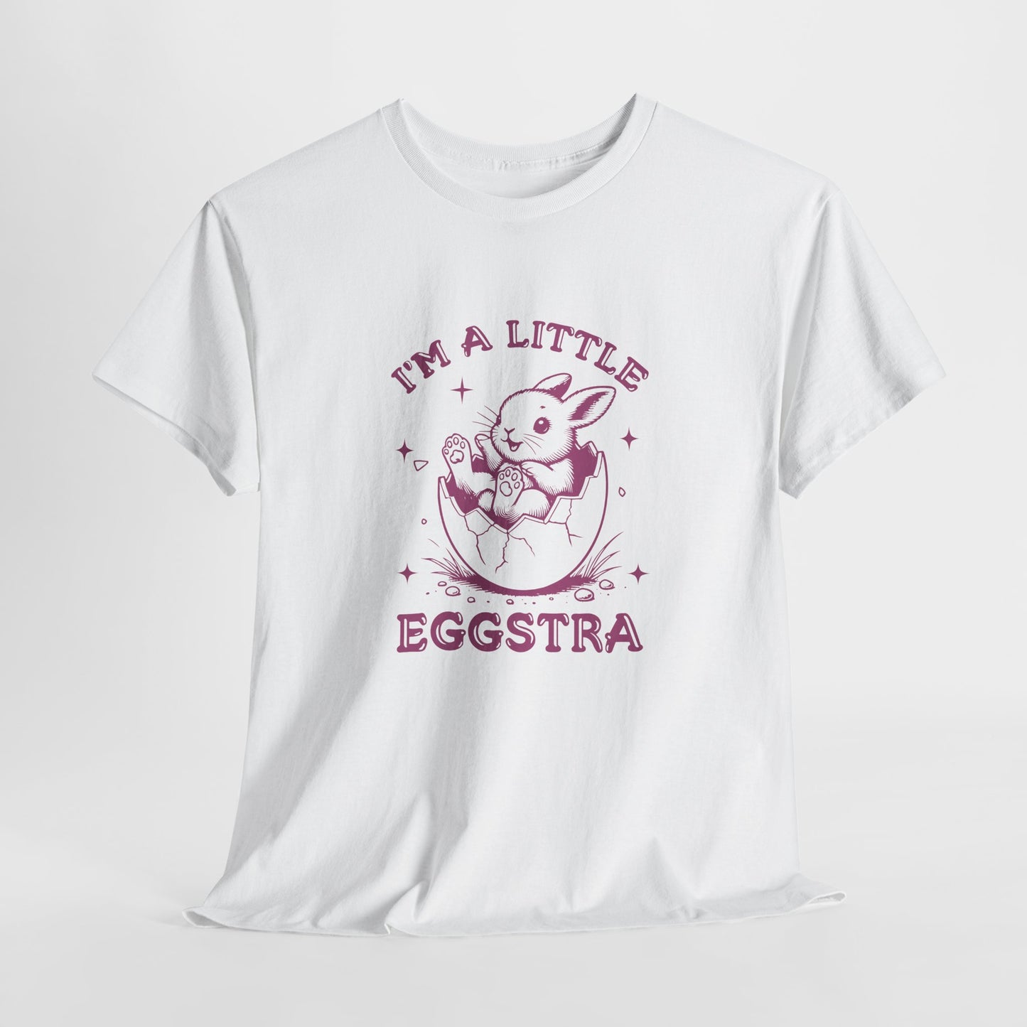 White Easter T-shirt hanging, showcasing a playful bunny and "I'm A Little Eggstra" text in a pink design, a stylish and festive choice. Hop into the season in style and shop Easter shirts online today!