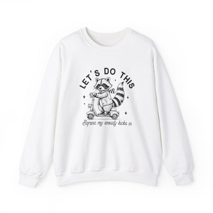 Front view of a white sweatshirt featuring a cartoon raccoon riding a scooter with the text "Let's Do This Before My Anxiety Kicks In." Part of the Vivid Divergence Sensory Friendly Unisex Sweater Jumper Range.