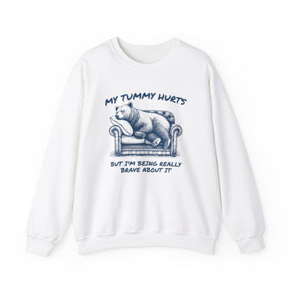 Front view of a white sweater jumper with the text "My Tummy Hurts But I’m Being Really Brave About It" and a cartoon illustration of a bear holding its stomach. Part of the Vivid Divergence Sensory Friendly Unisex Sweater Jumper Range.