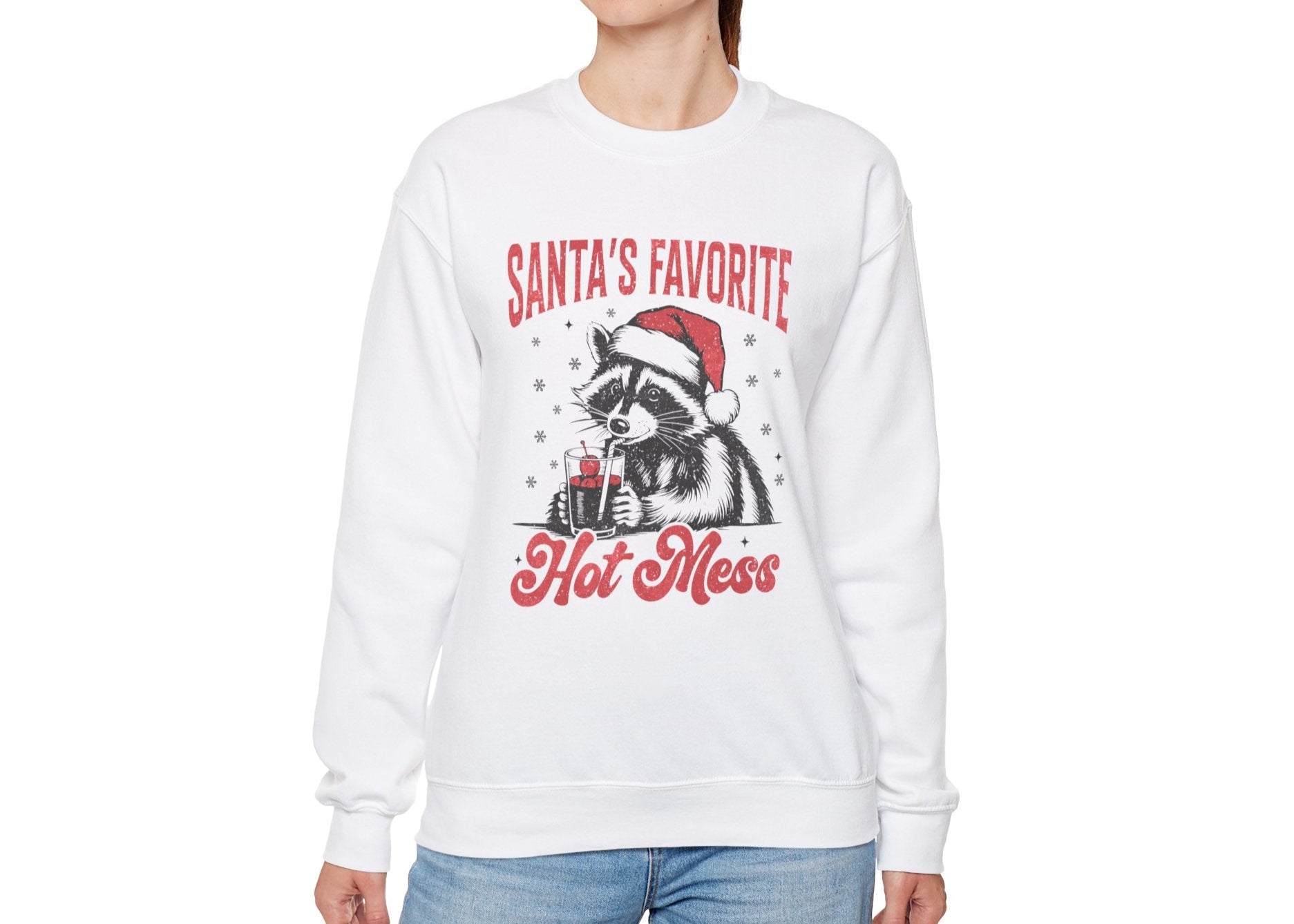 Another model wearing a white sweatshirt featuring a "Santa's Favorite Hot Mess" design with a festive raccoon wearing a Santa hat. Part of the Vivid Divergence Sensory Friendly Unisex Sweater Jumper Range.