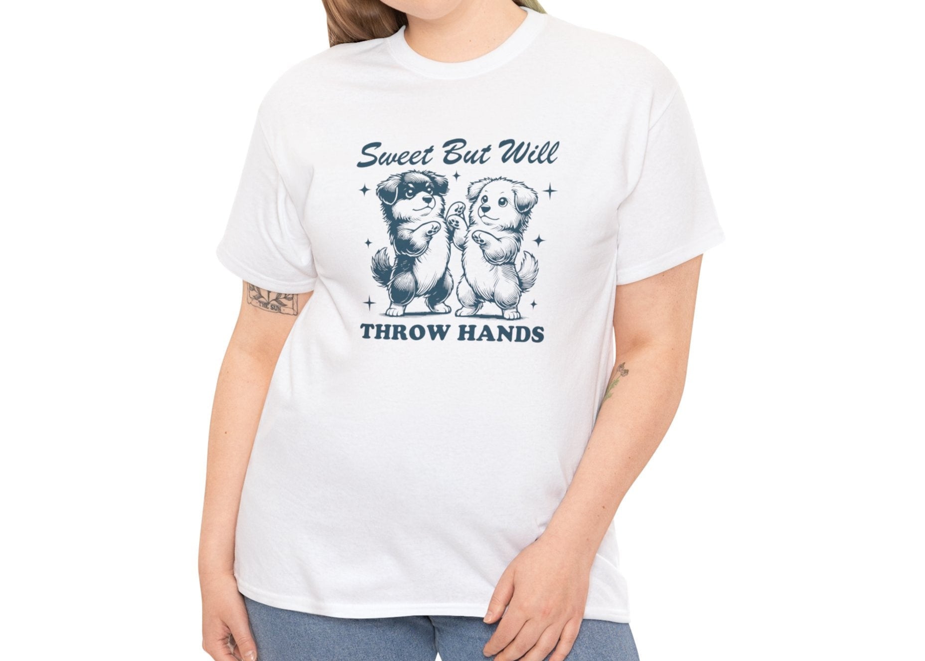 Model with curly hair wearing a white T-shirt featuring "Sweet But Will Throw Hands" text with two dogs in navy blue-tone design. Part of the Vivid Divergence Sensory Friendly Unisex Tees Range.