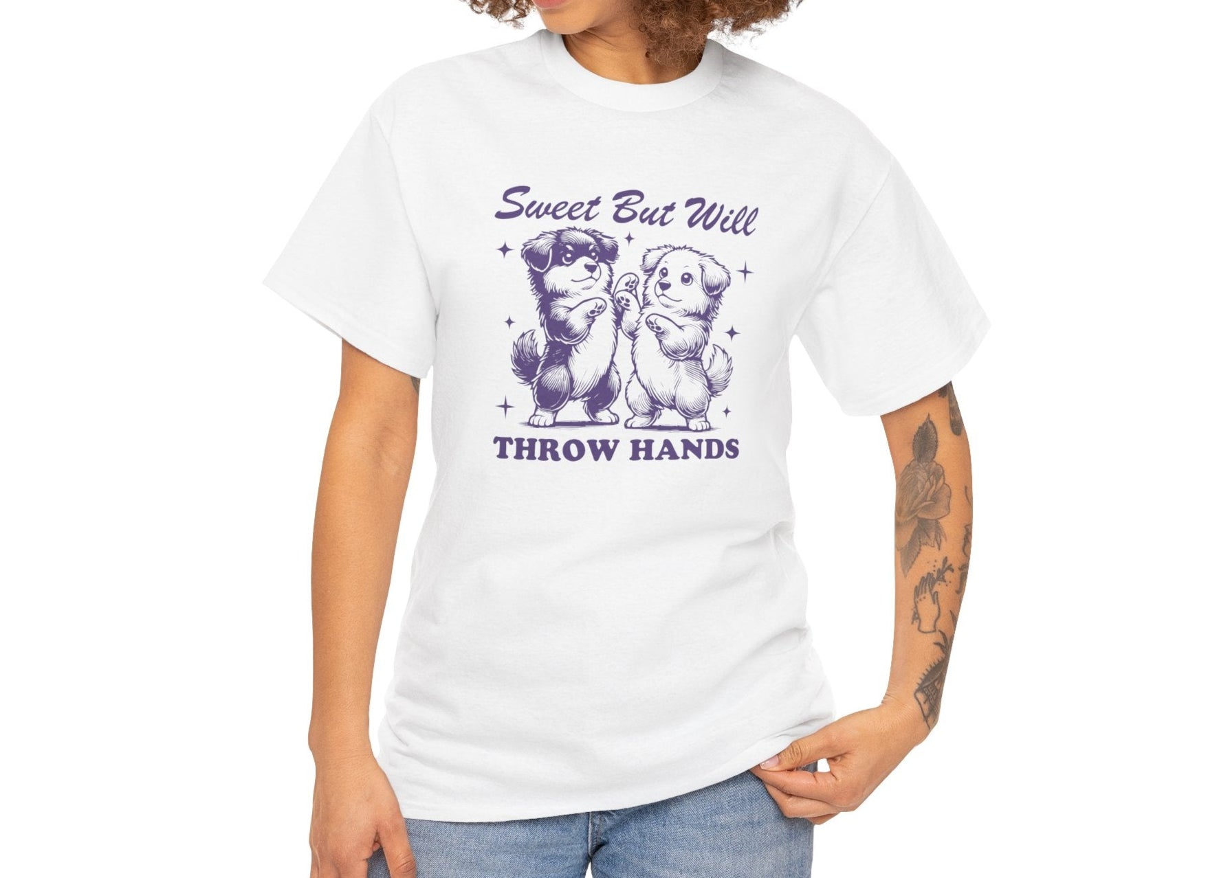Model wearing a white T-shirt featuring "Sweet But Will Throw Hands" text with two dogs in purple-tone design. Part of the Vivid Divergence Sensory Friendly Unisex Tees Range.