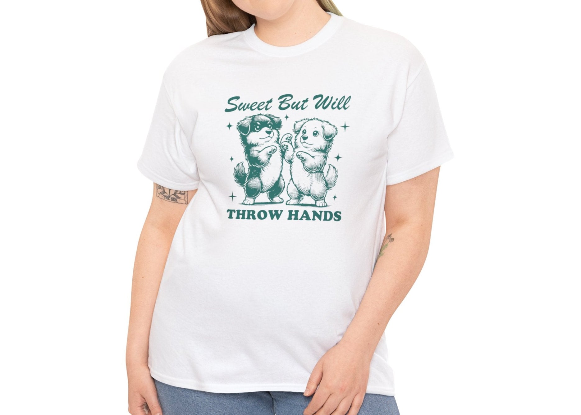 Model wearing a white T-shirt featuring "Sweet But Will Throw Hands" text with two dogs in teal-tone design. Part of the Vivid Divergence Sensory Friendly Unisex Tees Range.