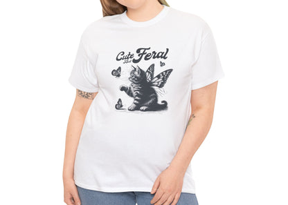 Model wearing a white T-shirt with "Cute but Feral" cat and butterfly design, styled casually. Part of the Vivid Divergence Sensory Friendly Unisex Tees Range.