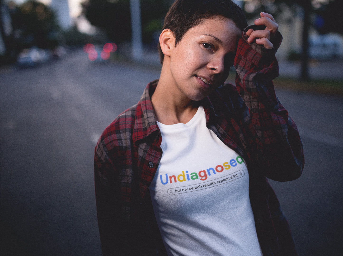Model wearing a white T-shirt with the text "Undiagnosed" styled in the Google logo font and colors, followed by the phrase "A Comprehensive Self-Diagnosis." Part of the Vivid Divergence Sensory Friendly Unisex Tees Range.