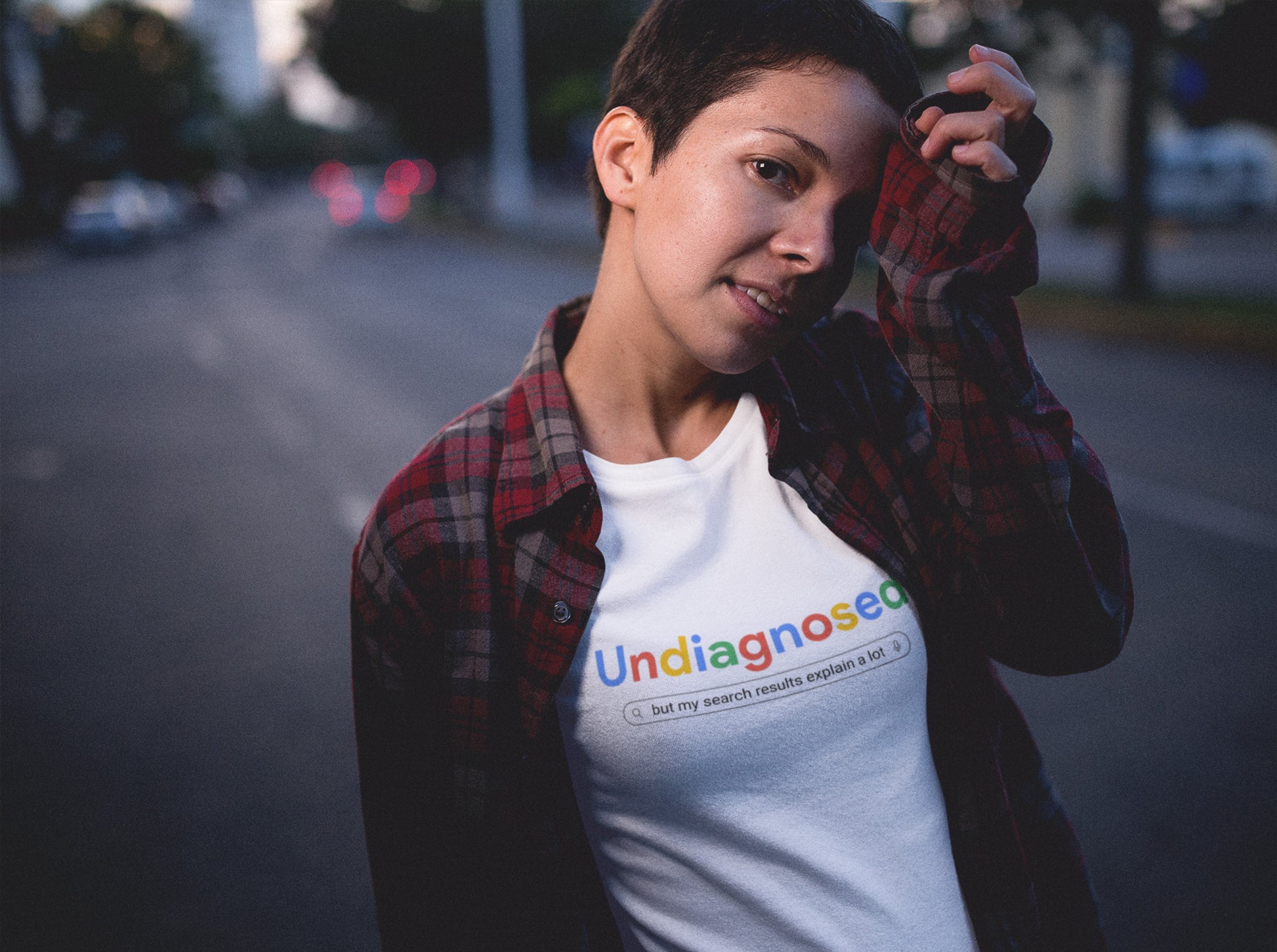 Model wearing a white T-shirt with the text "Undiagnosed" styled in the Google logo font and colors, followed by the phrase "A Comprehensive Self-Diagnosis." Part of the Vivid Divergence Sensory Friendly Unisex Tees Range.