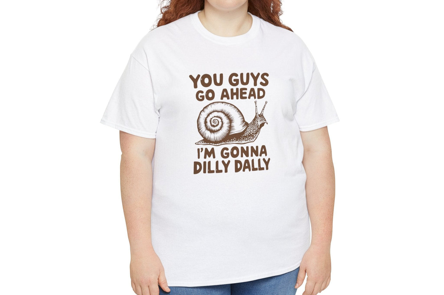 Model wearing a white T-shirt with the text "You Guys Go Ahead, I'm Gonna Dilly Dally" and a playful snail graphic in brown. Part of the Vivid Divergence Sensory Friendly Unisex Tees Range.