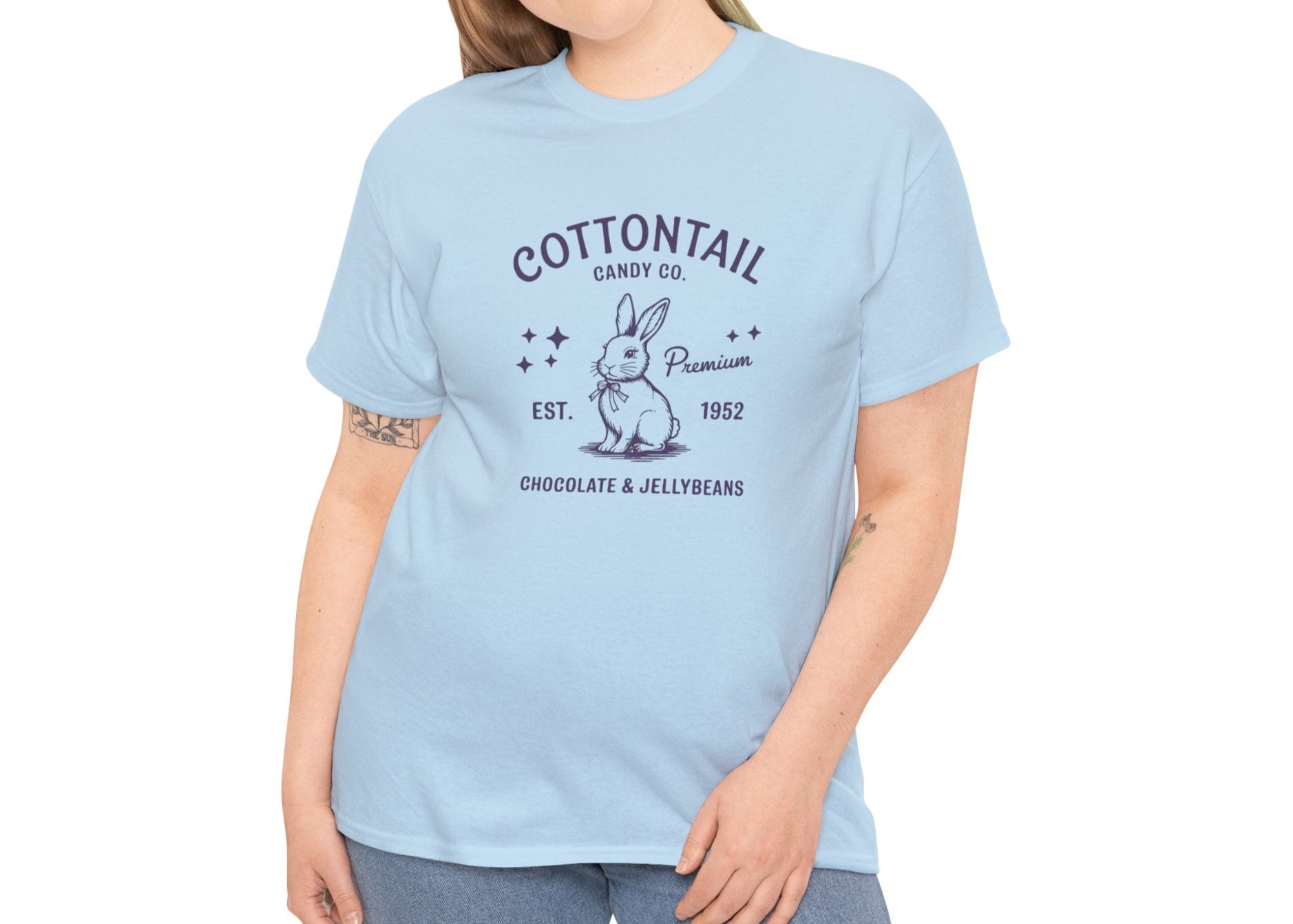 Woman wearing a light blue Easter T-shirt with a timeless "Cottontail Candy Co." bunny design, perfect for a classic spring look. Hop into the season in style and shop Easter shirts online today!