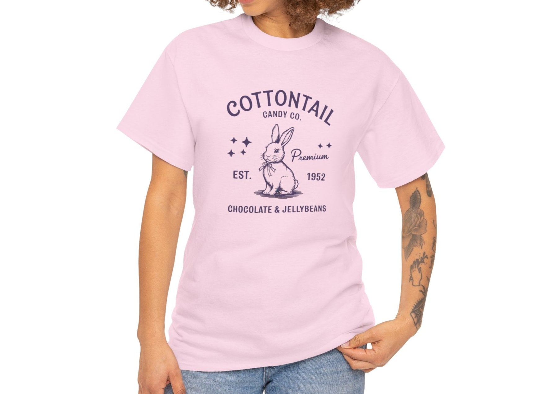 Woman wearing a light pink Easter T-shirt showcasing a nostalgic "Cottontail Candy Co." bunny logo, blending vintage charm with festive fun. Hop into the season in style and shop Easter shirts online today!