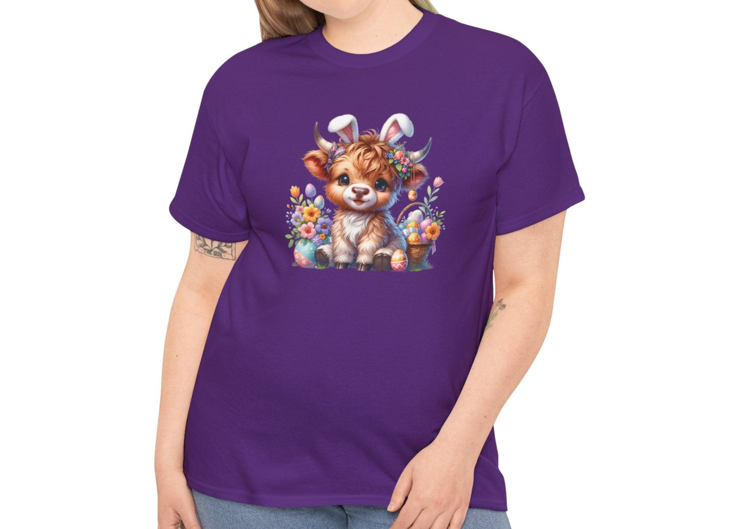 Woman wearing a purple Easter T-shirt decorated with a sweet Highland cow surrounded by spring flowers, a stylish and fun holiday look. Hop into the season in style and shop Easter shirts online today!